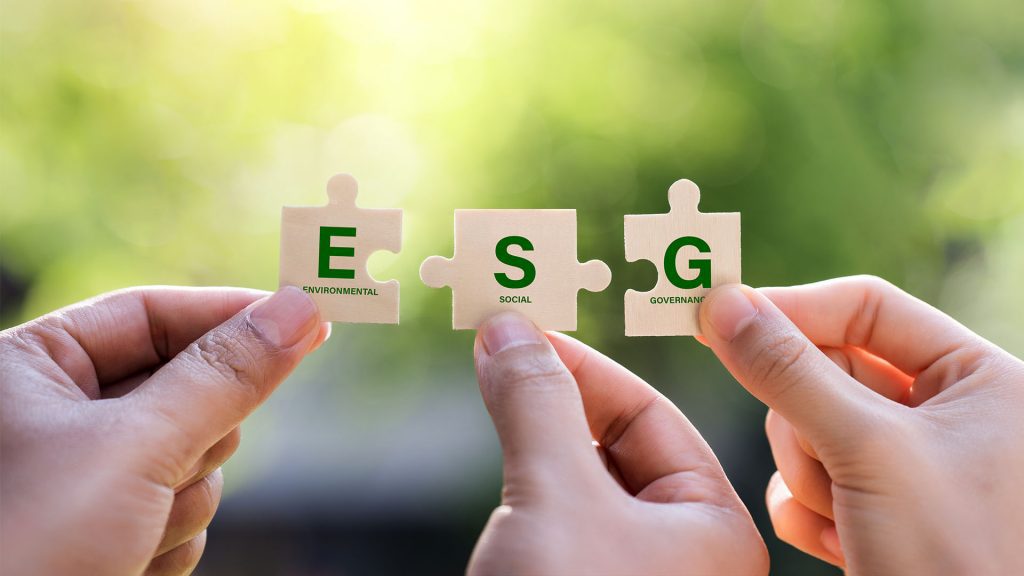 Hands holding jigsaw with words ESG for environmental, social, and governance in sustainable and ethical business on the Network connection on a green background.