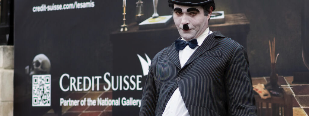 Charlie Chaplin street performer with the Credit Suisse billboard behind.
